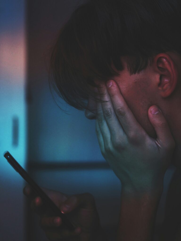 Moody close-up portrait of a person looking at a smartphone screen in low light